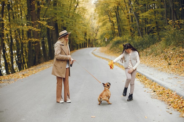 Vrouw, klein meisje en hond wandelen in het herfstpark