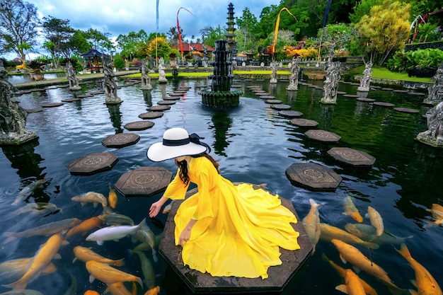 Vrouw kleurrijke vissen voederen in de vijver bij Tirta Gangga Water Palace in Bali, Indonesië