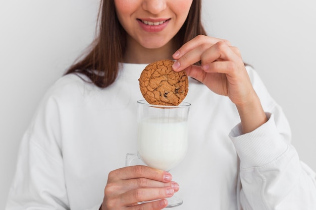 Vrouw koekje in melk onderdompelen