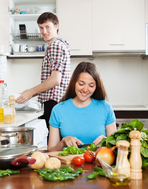 vrouw koken voedsel terwijl man afwassen