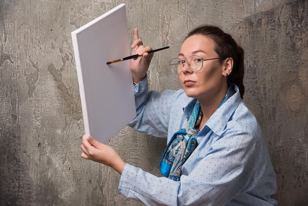 Vrouw kunstenaar toont haar canvas met penseel op marmer