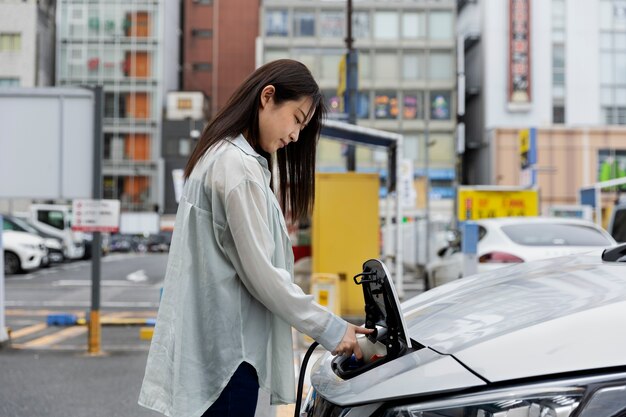 Vrouw laadt haar elektrische auto op bij het station