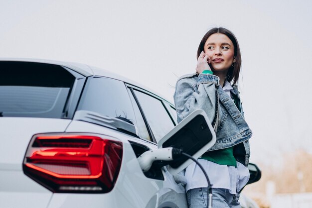 Vrouw laadt haar elektrische auto op met oplaadpistool