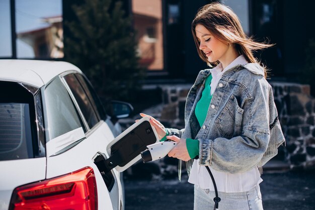 Vrouw laadt haar elektrische auto op met oplaadpistool