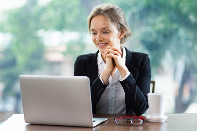 Vrouw lachend te kijken naar een laptop