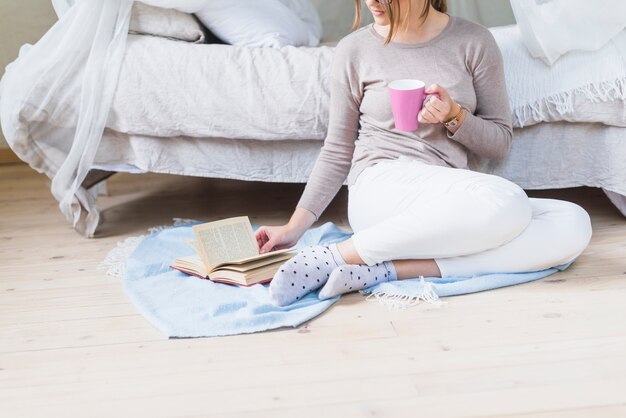 Vrouw leesboek bedrijf kopje koffie