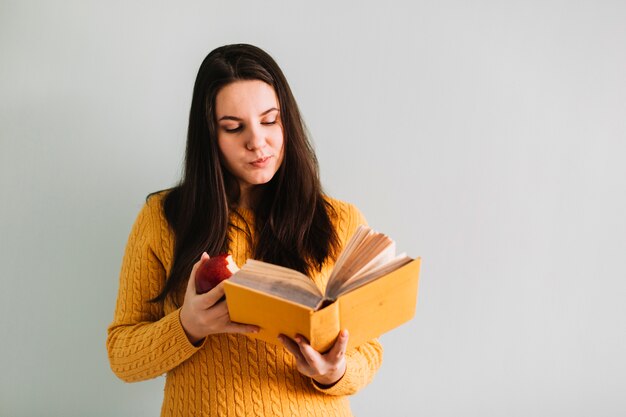 Vrouw leesboek en appel eten