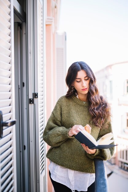 Vrouw leesboek op balkon