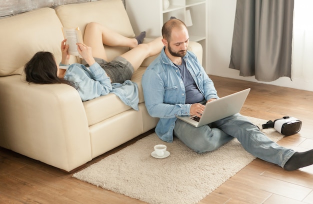 Vrouw leest een boek dat op de bank in de woonkamer ligt