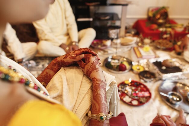 Vrouw ligt haar mooie handen bedekt met mehndi over haar knie