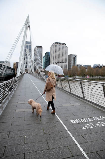 Vrouw loopt met haar hond op een brug terwijl het regent