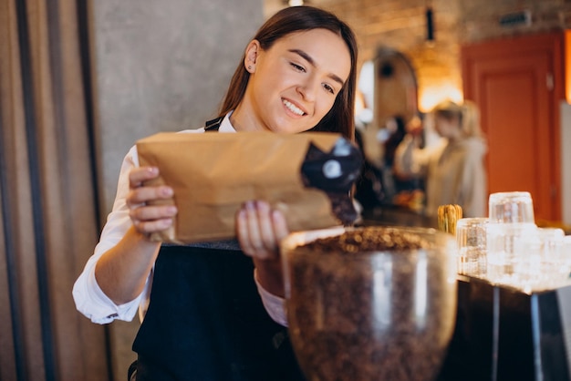 Vrouw maalt koffie in koffiezetapparaat