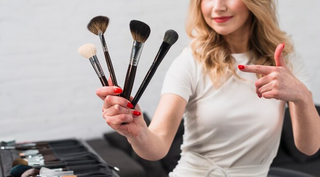 Vrouw make-up artiest wijzend op make-up borstels