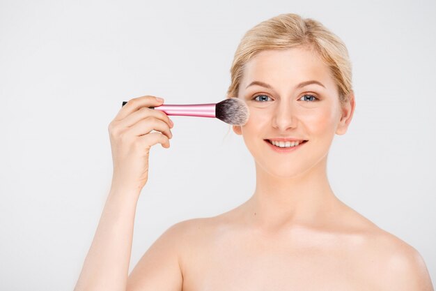 vrouw make-up op gezicht met borstel toepassen