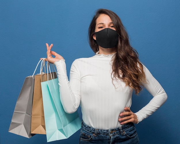 Gratis foto vrouw masker dragen en boodschappentassen te houden