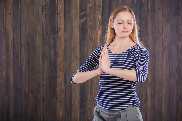 Gratis foto vrouw mediteren op houten achtergrond