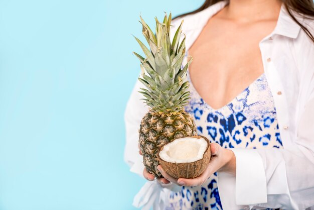 Gratis foto vrouw met ananas en kokosnoot