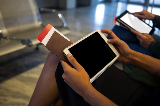 Vrouw met behulp van digitale tablet in wachtruimte op de luchthaven