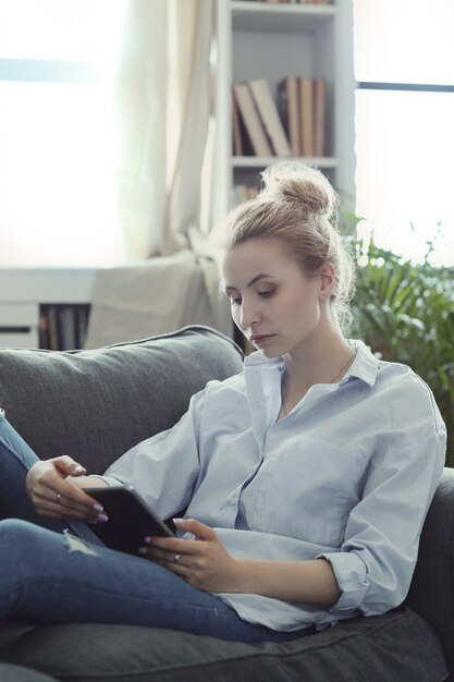 vrouw met behulp van digitale tablet, liggend op de bank