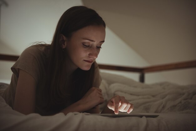 Vrouw met behulp van digitale tablet op bed