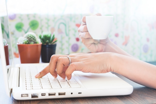 Gratis foto vrouw met behulp van laptop en koffie thuis drinken, werk thuis concept