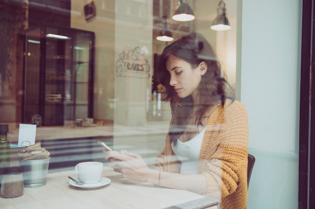 Gratis foto vrouw met behulp van smartphone in café