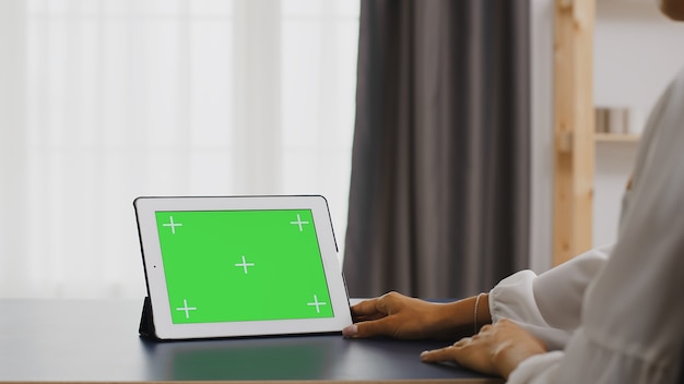 Vrouw met behulp van tablet pc met groen scherm in kantoor aan huis.