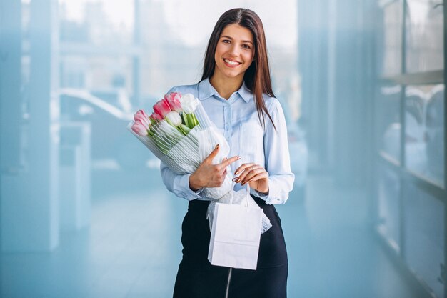 Vrouw met bloemen in een autotoonzaal