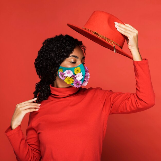 Vrouw met bloemen op haar masker poseren met hoed