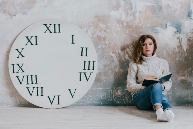 Vrouw met boek dichtbij klokschijf