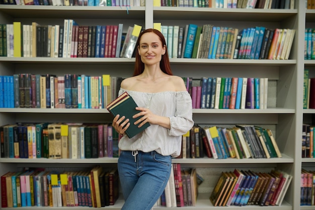 Vrouw met boeken op de achtergrond van boekenplanken