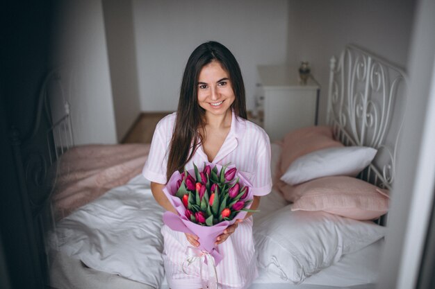 Vrouw met boeket bloemen in de slaapkamer