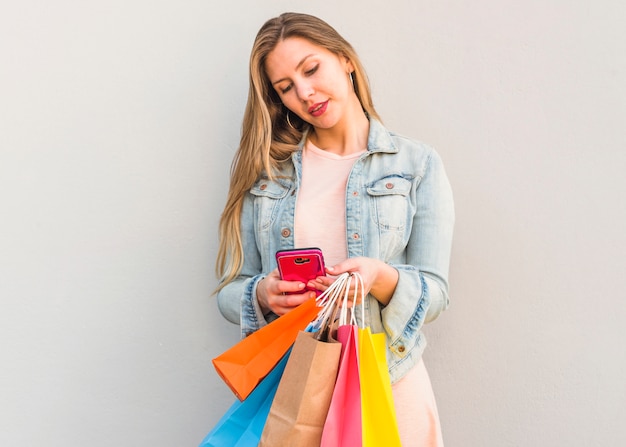 Vrouw met boodschappentassen met behulp van smartphone