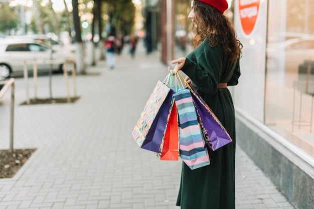 Gratis foto vrouw met boodschappentassen op zaak op straat