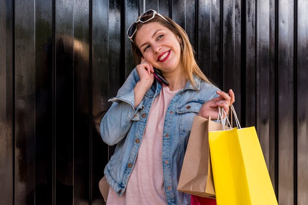 Vrouw met boodschappentassen praten via de telefoon