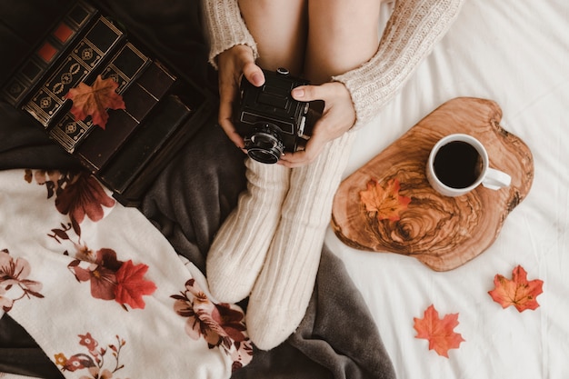 Vrouw met camera in de buurt van boeken en thee bijsnijden