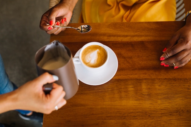 Vrouw met cappuccino-kop op houten lijst