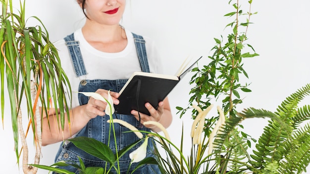 Gratis foto vrouw met dagboek in de buurt van planten