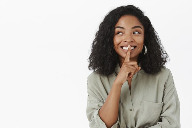 Vrouw met donkere huid glimlachend vreugdevol idee hebben starend naar links en vragen geheim houden