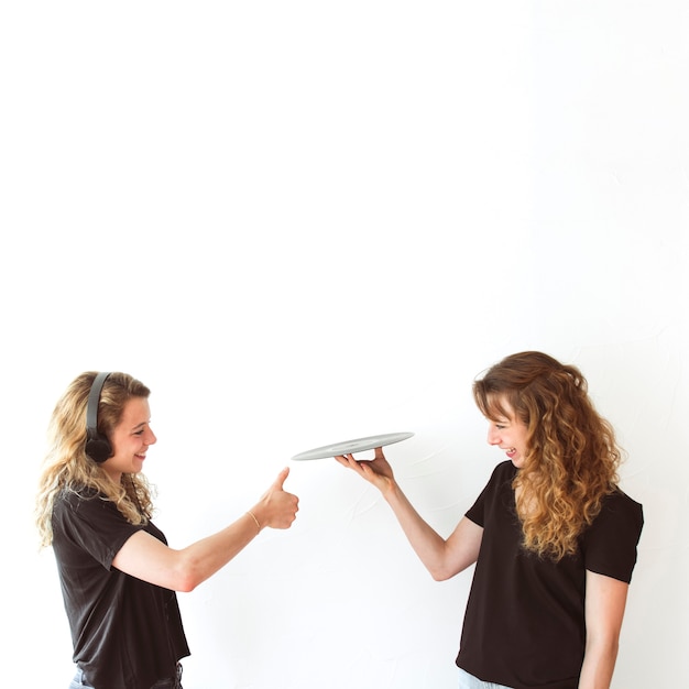 Vrouw met duim omhoog teken naar haar zus balancing vinyl record in de hand