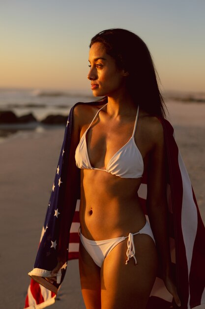 Vrouw met een Amerikaanse vlag die zich op het strand bevindt