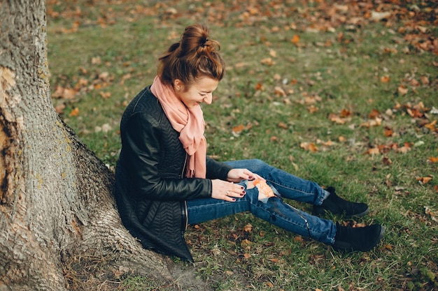 Vrouw met een beenblessure. Het gewonde meisje dat bij de boom zit. De wond bloedt.