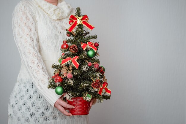 vrouw met een kerstboom op grijze muur