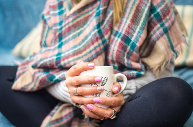 Vrouw met een kopje koffie gekleed in warme winterkleren zittend