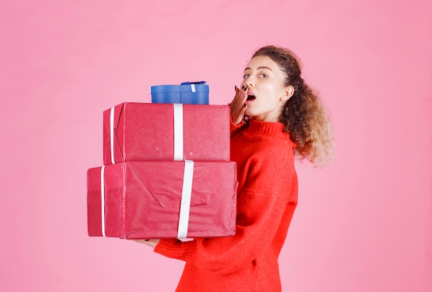 vrouw met een voorraad grote geschenkdozen en kijkt verrast.