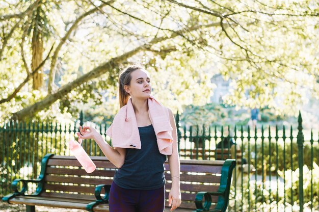 Vrouw met fles en handdoek in park