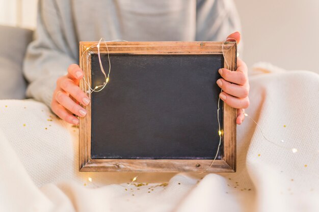 Vrouw met fotolijst met fairy lichten