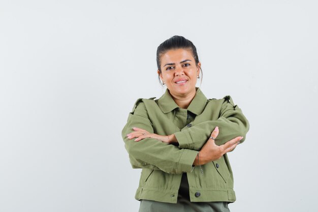 vrouw met gekruiste armen in jas, t-shirt en op zoek vrolijk