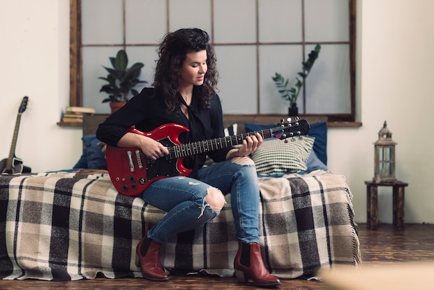 Vrouw met gitaar zittend op bed