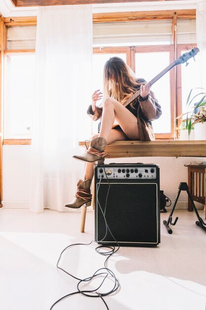 Vrouw met gitaar zittend op tafel